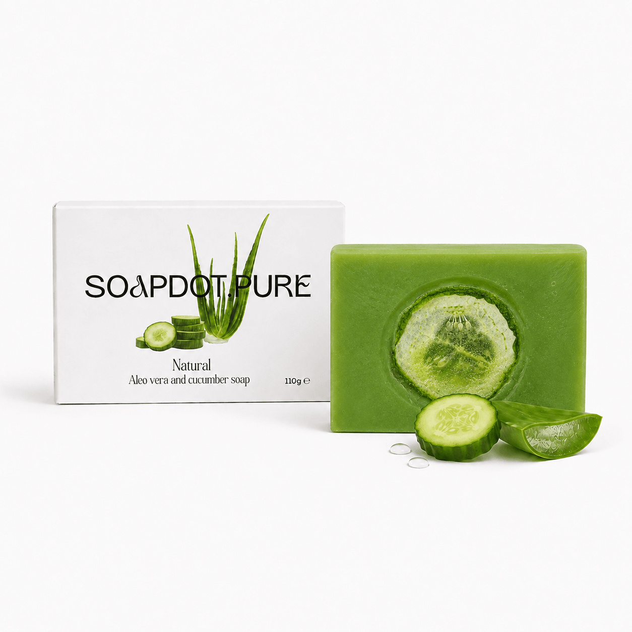 A bar of green aloe vera and cucumber soap stands in front of its white packaging box, which features aloe and cucumber illustrations. The soap bar has a circular cutout showing a cucumber slice, with cucumber slices and a small metal ring prop placed in front on a clean white background.